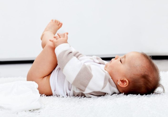 an infant lies on her back without a diaper