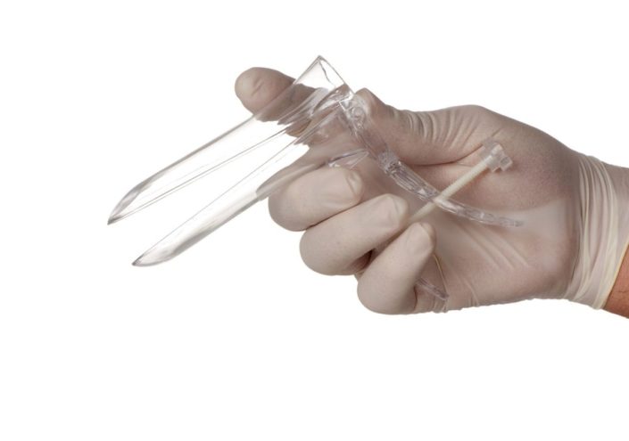 A doctor’s gloved hand holding a disposable speculum