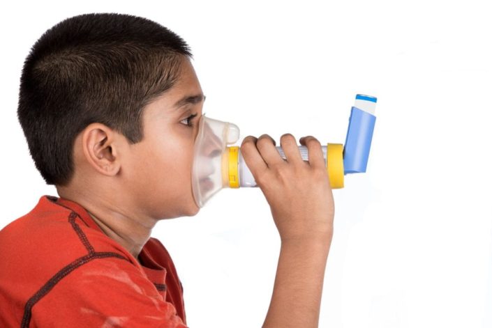 young boy using spacer and mask with asthma inhaler