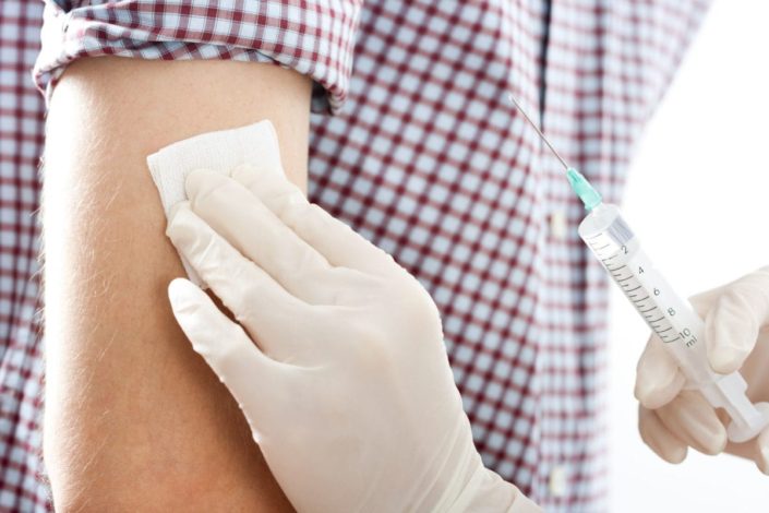 A close-up of a boy getting an injection in his right upper arm