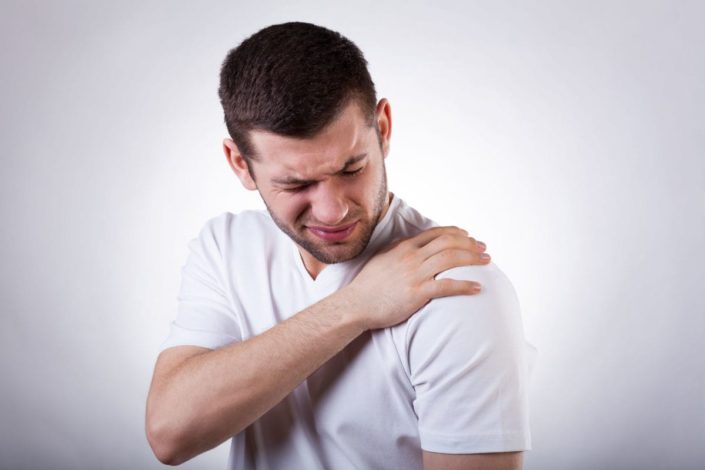 A young man grabbing his shoulder in pain