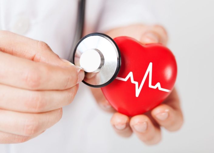 A doctor holding a stethoscope up to a toy heart