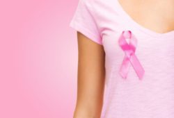 woman dressed in pink wears a pink ribbon on her chest