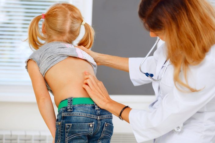 Pediatrician examining little girl with back problems.