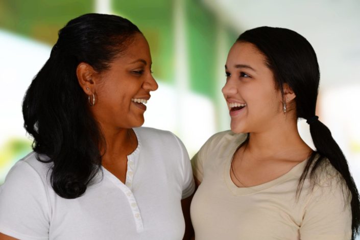 mother and daughter embrace and smile at each other