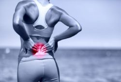 Athletic woman standing outside, rubbing lower back muscles. Low back pain is a common problem and has many possible causes, including injury, pregnancy and poor posture.