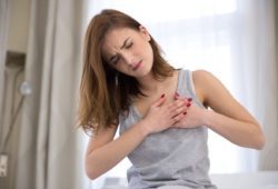 A woman having chest pains, with her hands over her heart