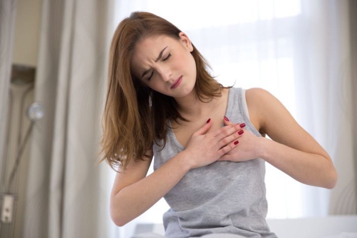 A woman having chest pains, with her hands over her heart