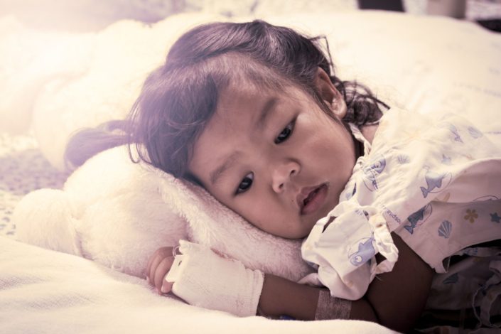 A sick little girl lies in a hospital bed. Knowing when to take your child to the emergency room can be a difficult decision, but there are things you can look for to make it easier.