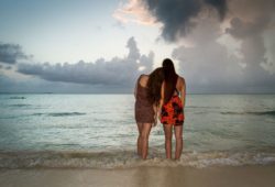 Two young girls standing together on a beach