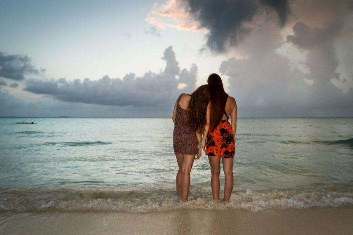Two young girls standing together on a beach