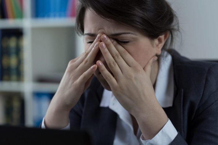 Woman in business clothes holding sinuses in pain
