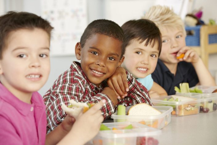 group of young children eating healthy lunches at school