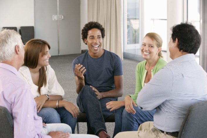 a support group sits in a circle and laughs