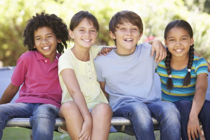 group of happy children sitting on the edge of a trampoline outside