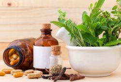 bowl of fresh herbs, plus dried herbs and capsules on a table