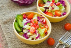 Two bowls of healthy salad on table with forks