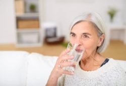 Middle-aged woman drinks a glass of water in the living room. Diabetes insipidus is a hormone disorder that causes extreme thirst and increased urination. It can be treated with medication.
