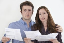 young couple looking confused about their bills