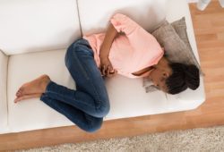 woman with stomach ache lying on sofa