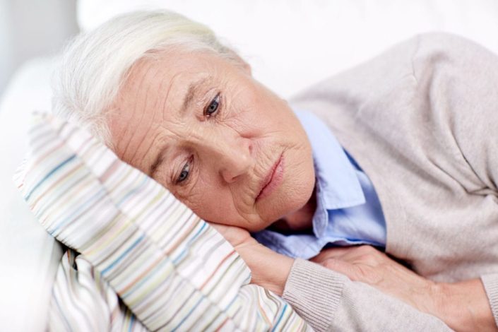 Elderly, depressed woman lying on pillow
