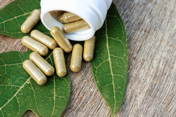 Plant sterols and stanols supplements in capsules spilling out from a white bottle