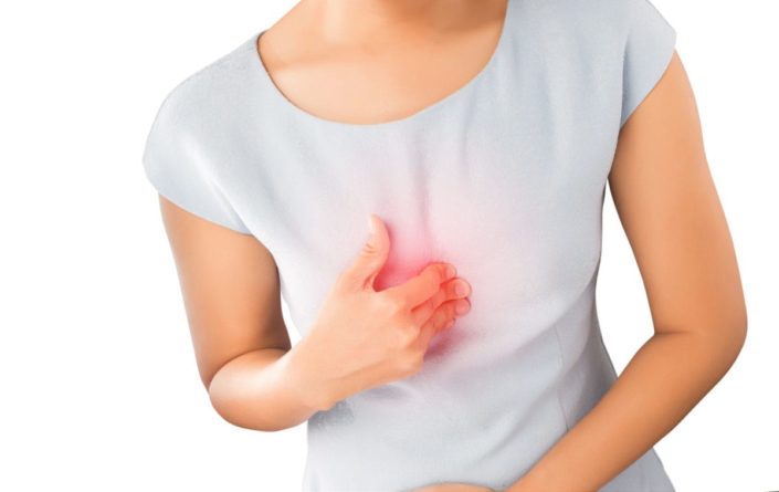 A woman pressing on her chest due to heartburn pain