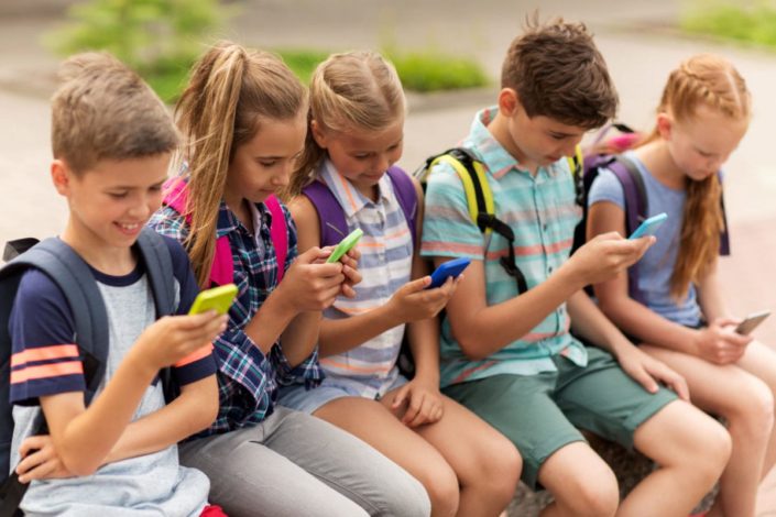 group of early teens sitting together playing on phones