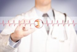 close-up of a doctor holding a pill, focused on a heartbeat graph