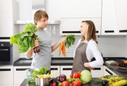 Two family members in the kitchen cooking a meal with lots of vegetables