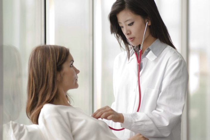 doctor using stethoscope to listen to woman’s heart