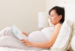 pregnant woman in bed reading a book