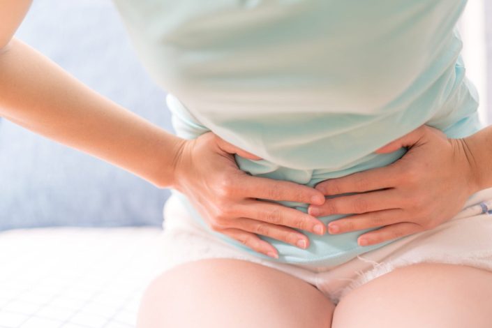 close up of a woman holding her abdomen in discomfort