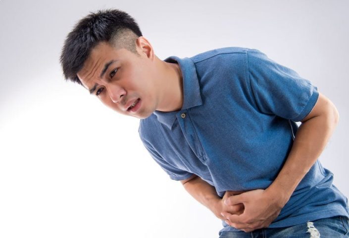 A men bent over clutching his side in pain due to appendicitis symptoms.