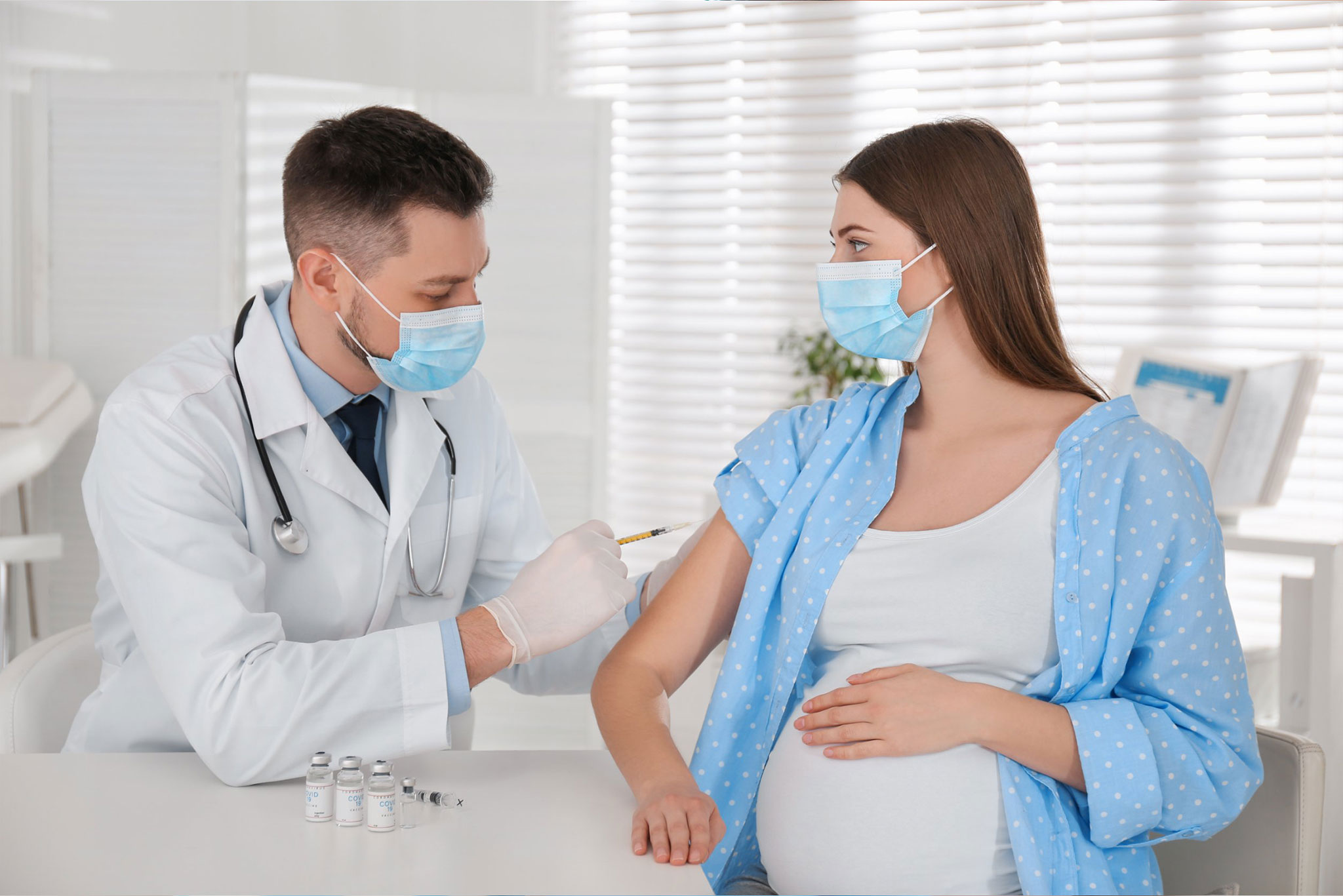 A doctor vaccinates a pregnant woman in a clinical setting.