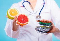a doctor holding grapefruit in one hand and medication in the other