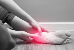 A woman rubs her heel to relieve plantar fasciitis symptoms.