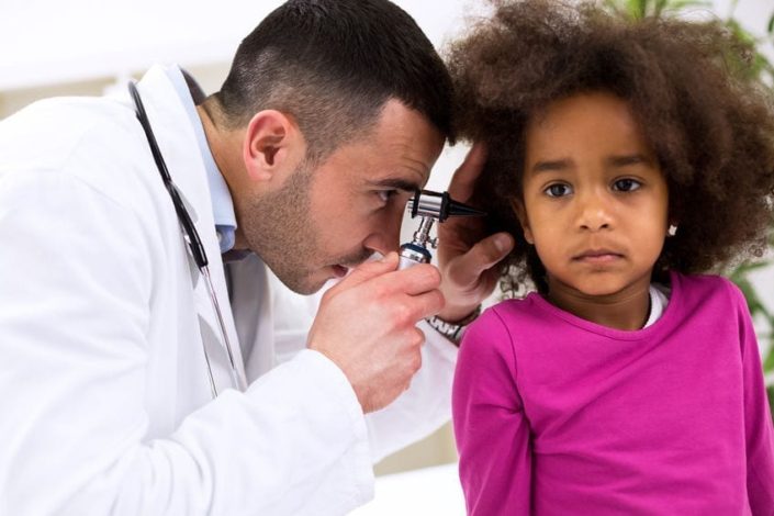 A doctor using a otoscope to look inside a young girls ear canal