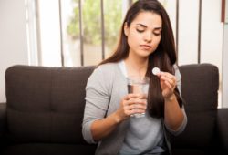 Woman holding antacid tablet and glass of water