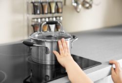 Young child touching hot pot on the stove
