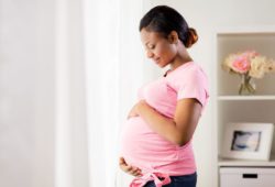 A happy pregnant woman holds her pregnant belly. The third trimester of pregnancy starts at 28 weeks and signals the last phase before giving birth. Your body may experience physical changes.