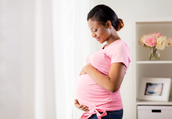 A happy pregnant woman holds her pregnant belly. The third trimester of pregnancy starts at 28 weeks and signals the last phase before giving birth. Your body may experience physical changes.